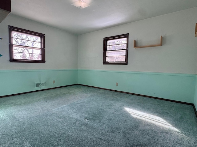 carpeted spare room featuring baseboards and visible vents