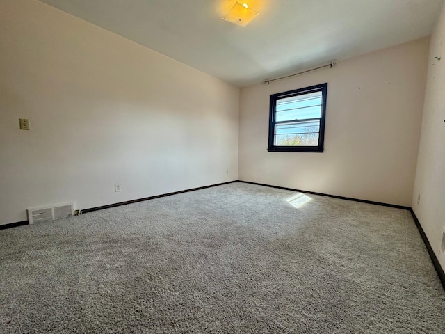 carpeted spare room featuring baseboards and visible vents