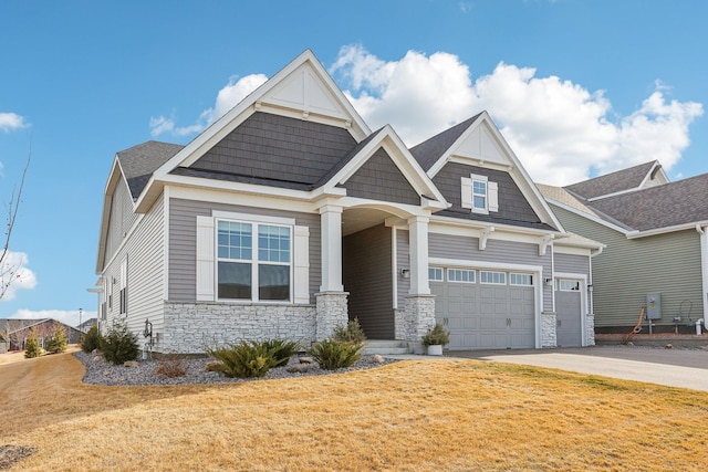 craftsman-style house with an attached garage, driveway, stone siding, and a front lawn