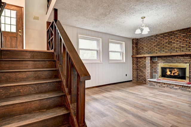 21414 Tulip St NW, Oak Grove, MN 55303 - unfurnished living room with stairway, a chandelier, wood finished floors, a textured ceiling, and a fireplace