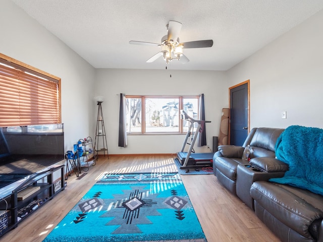 interior space with a textured ceiling, wood finished floors, baseboards, and ceiling fan