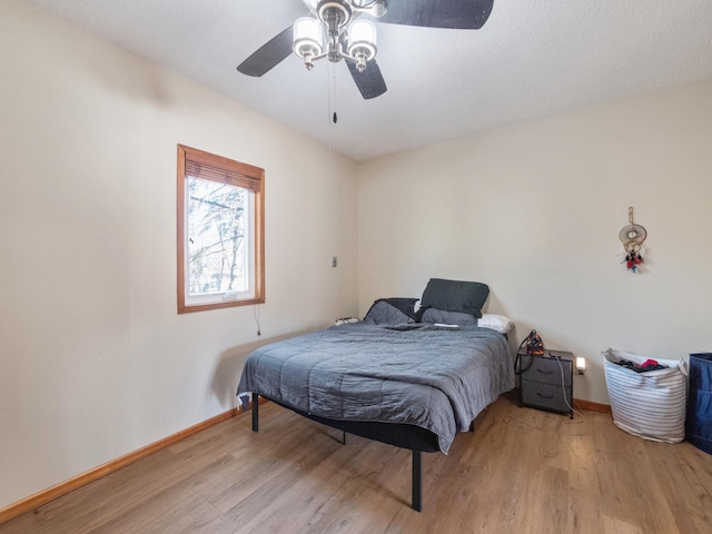 bedroom featuring a ceiling fan, baseboards, and wood finished floors