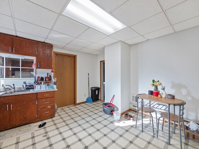 kitchen featuring a drop ceiling, light floors, light countertops, and a sink