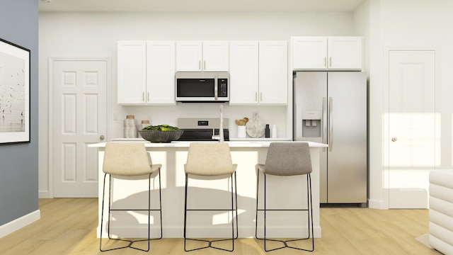 kitchen featuring light wood-type flooring, appliances with stainless steel finishes, a breakfast bar area, and white cabinetry