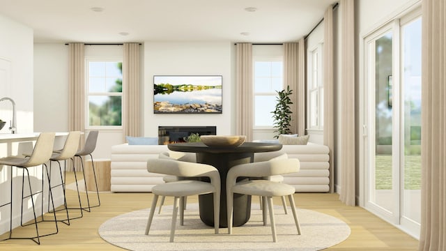 dining area featuring a glass covered fireplace and light wood-style floors