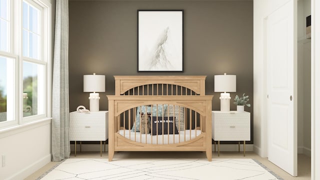 bedroom featuring a nursery area and baseboards