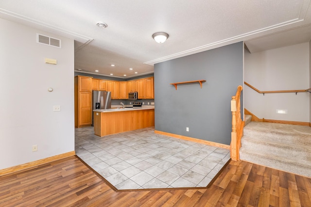 kitchen with baseboards, visible vents, light wood finished floors, stainless steel appliances, and light countertops