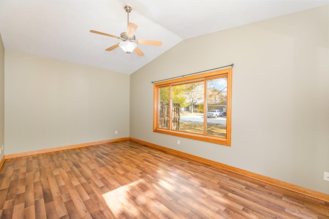 empty room with light wood finished floors, ceiling fan, baseboards, and vaulted ceiling