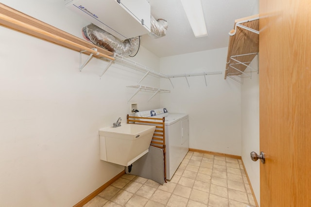 clothes washing area featuring a sink, laundry area, baseboards, and washing machine and clothes dryer