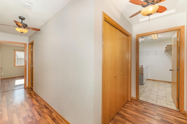 corridor featuring light wood-style flooring and baseboards