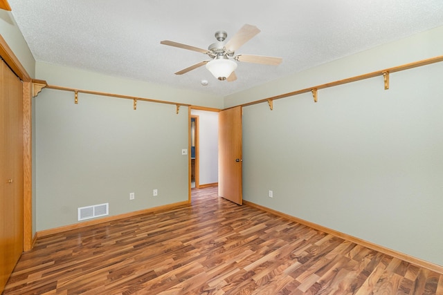 empty room with baseboards, visible vents, light wood finished floors, ceiling fan, and a textured ceiling