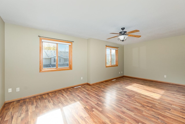 empty room with visible vents, baseboards, light wood-style floors, and ceiling fan