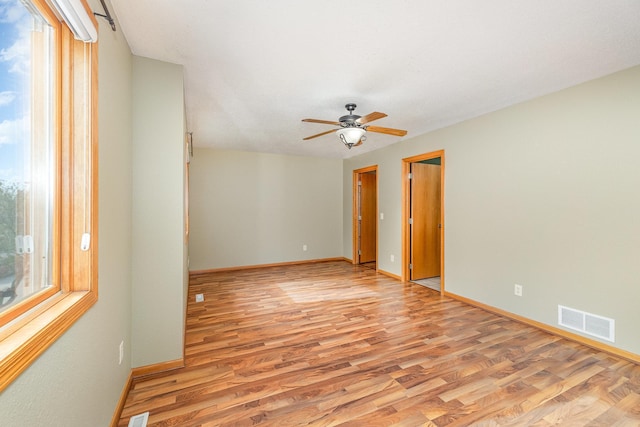 unfurnished room with light wood finished floors, visible vents, ceiling fan, and baseboards