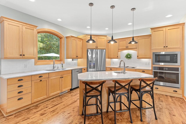 kitchen with light brown cabinets, light wood-style flooring, appliances with stainless steel finishes, and a sink