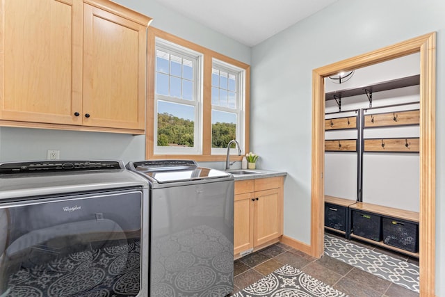 laundry area with a sink, baseboards, stone tile floors, cabinet space, and separate washer and dryer