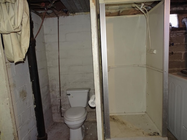 bathroom featuring concrete floors, toilet, and washer / dryer