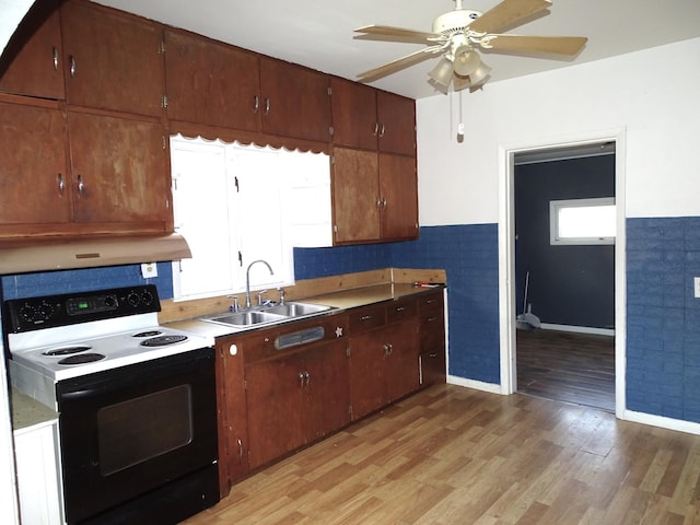 kitchen with light wood finished floors, range with electric cooktop, ventilation hood, and a sink