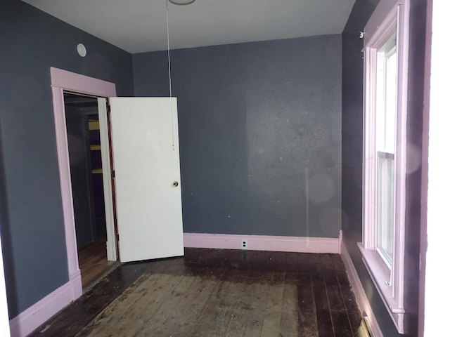 empty room featuring baseboards and wood-type flooring