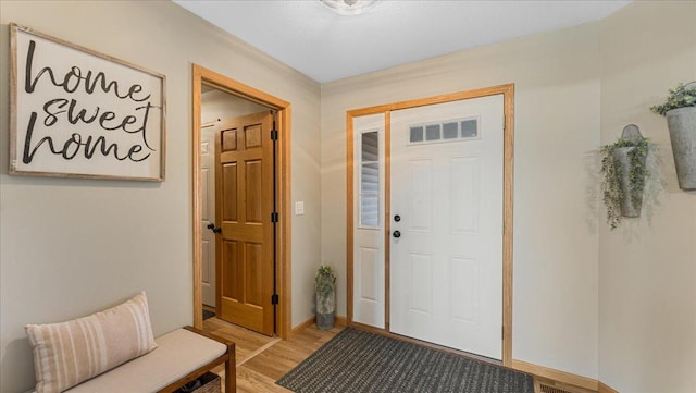 foyer with visible vents, baseboards, and light wood-style flooring