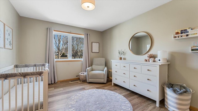 bedroom featuring visible vents, a crib, and light wood-style floors