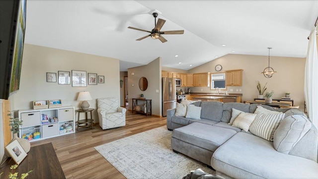 living area featuring recessed lighting, lofted ceiling, light wood-style floors, and ceiling fan with notable chandelier