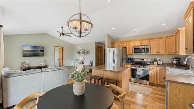 kitchen featuring a sink, open floor plan, appliances with stainless steel finishes, light wood finished floors, and lofted ceiling