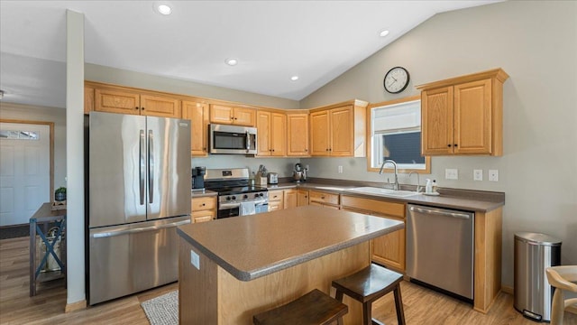 kitchen with light wood-type flooring, a sink, a center island, appliances with stainless steel finishes, and vaulted ceiling