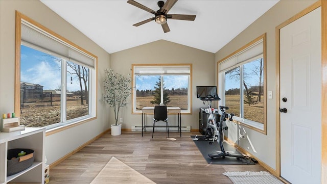 exercise room with a baseboard heating unit, lofted ceiling, wood finished floors, and a healthy amount of sunlight