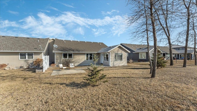 back of property with a residential view, a lawn, and a patio