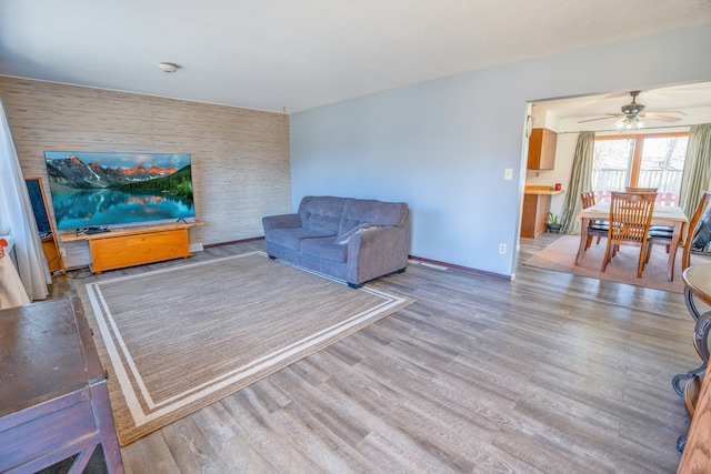 living room with baseboards, wood finished floors, and an accent wall