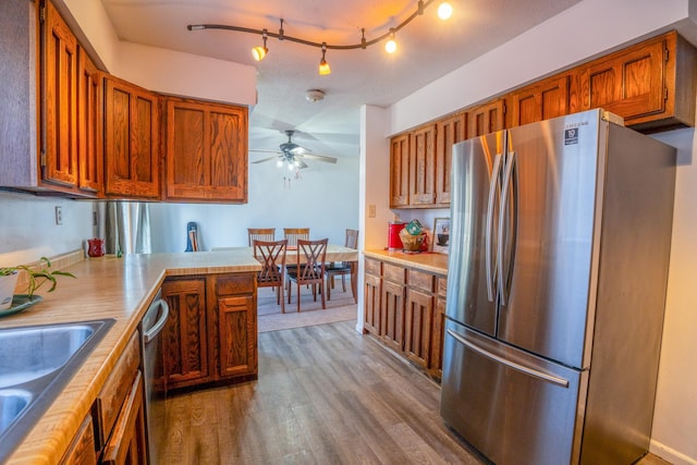 kitchen featuring light countertops, brown cabinetry, wood finished floors, and stainless steel appliances