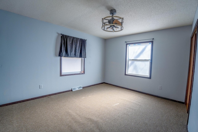 unfurnished bedroom featuring baseboards, visible vents, carpet floors, and a textured ceiling