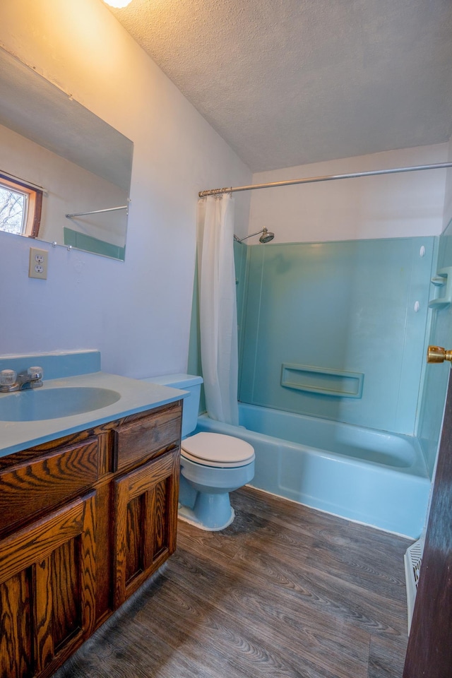 bathroom featuring toilet, vanity, shower / tub combo, wood finished floors, and a textured ceiling