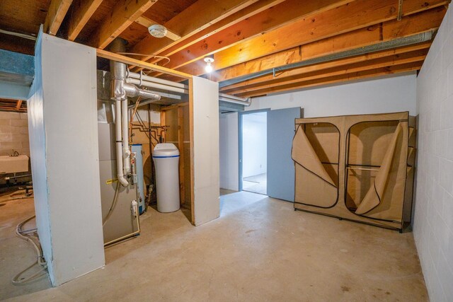 unfinished basement with gas water heater, concrete block wall, and a sink