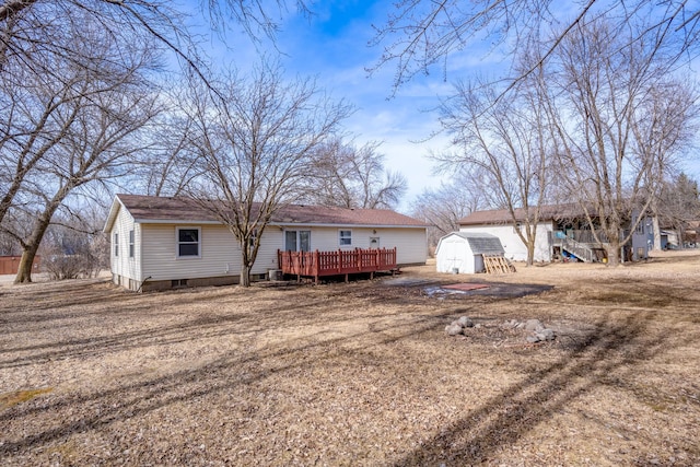 rear view of property featuring a wooden deck, an outbuilding, and a storage shed