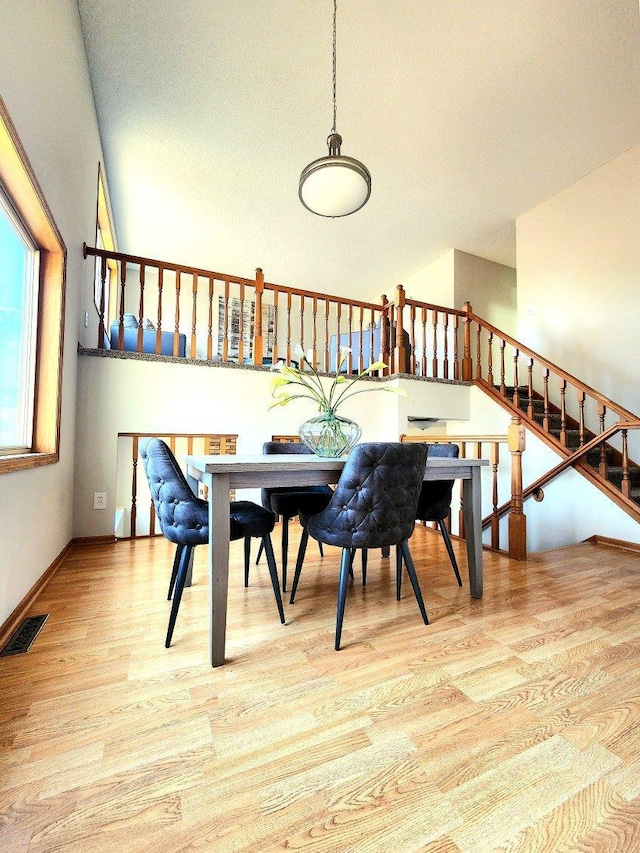 dining space featuring visible vents, baseboards, wood finished floors, and stairway