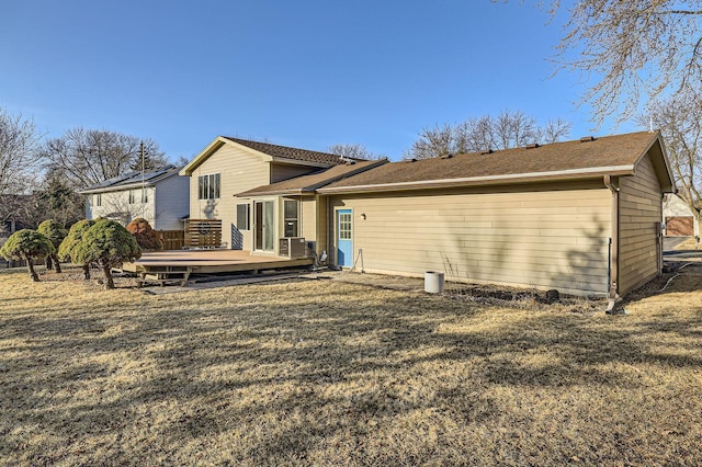 rear view of property featuring a wooden deck, a yard, and roof with shingles