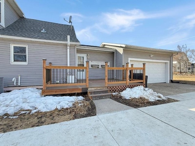 rear view of house featuring a garage, a wooden deck, driveway, and a shingled roof