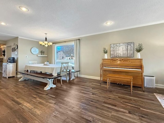 dining area featuring baseboards, a textured ceiling, wood finished floors, and crown molding