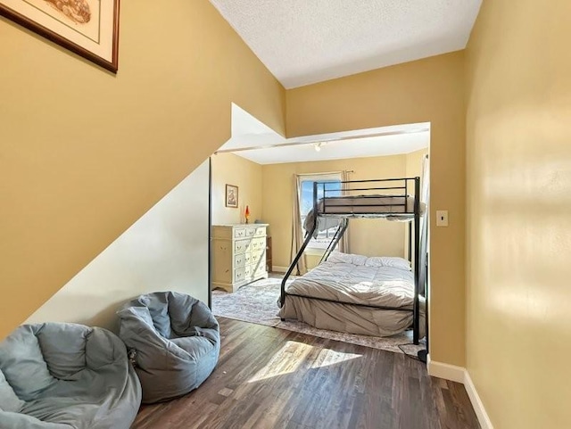 bedroom featuring wood finished floors, baseboards, and a textured ceiling