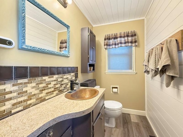 bathroom with toilet, backsplash, wood finished floors, crown molding, and vanity