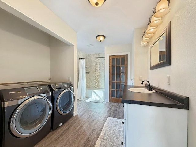 laundry room with a sink, wood finished floors, laundry area, and washer and clothes dryer