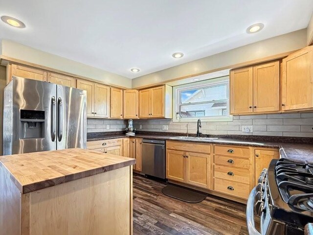 kitchen featuring light brown cabinets, a sink, dark wood-style floors, appliances with stainless steel finishes, and butcher block counters