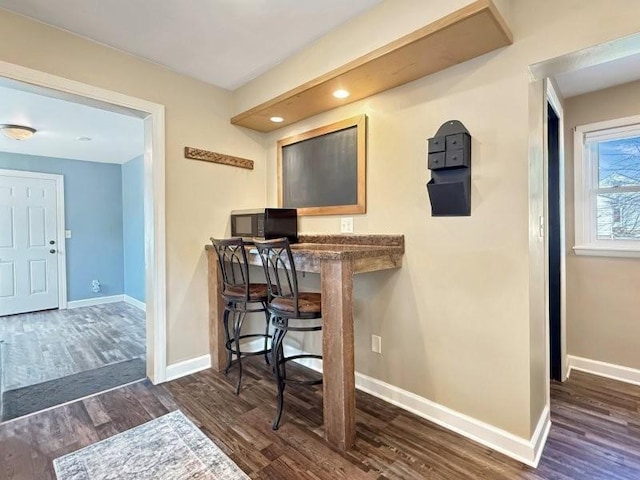 home office with baseboards and wood finished floors