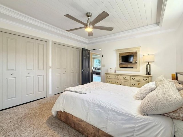 bedroom featuring multiple closets, a ceiling fan, light carpet, and crown molding