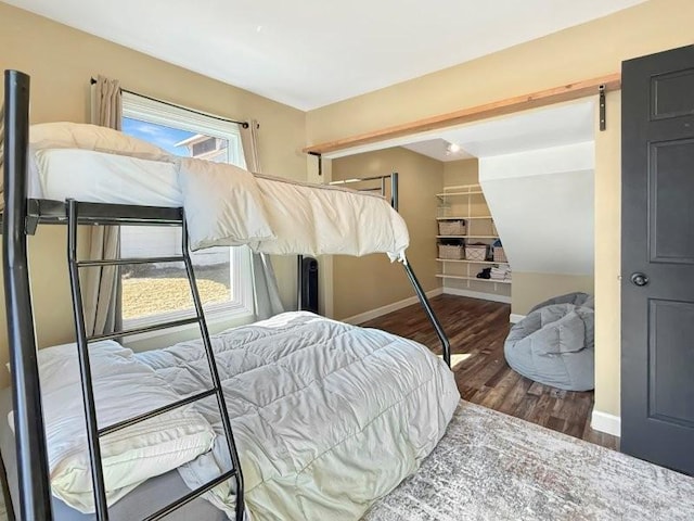 bedroom with a barn door, wood finished floors, and baseboards