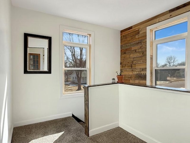 carpeted spare room with wooden walls and baseboards