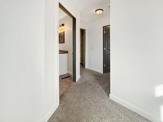 hall with visible vents, baseboards, and carpet