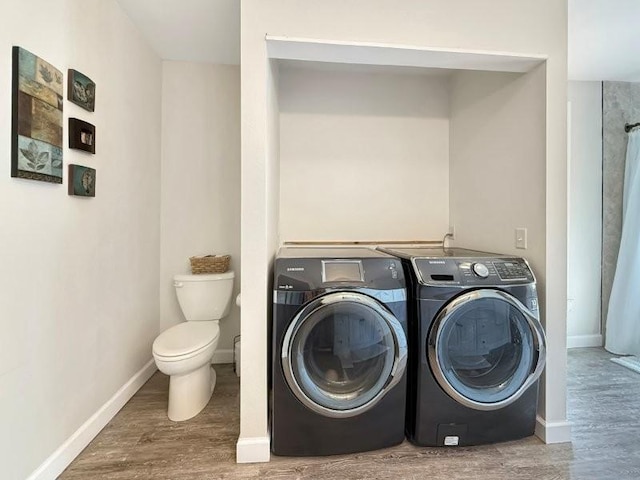 washroom with wood finished floors, baseboards, and washer and clothes dryer