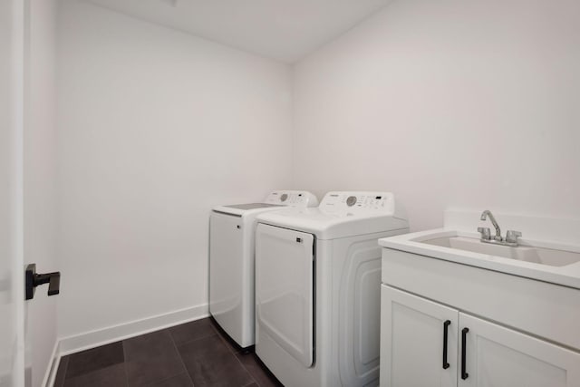 washroom featuring a sink, independent washer and dryer, baseboards, dark tile patterned flooring, and cabinet space